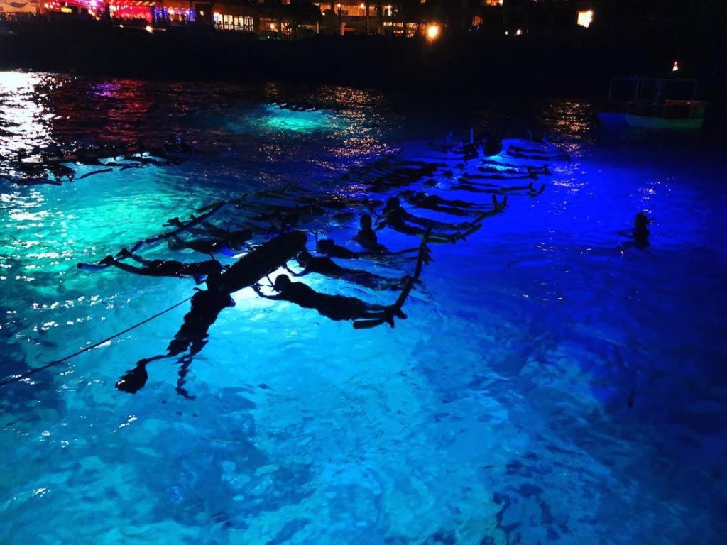 snorkelers on raft with manta rays