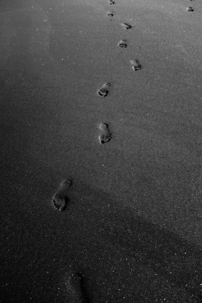Footprints on black sand beach